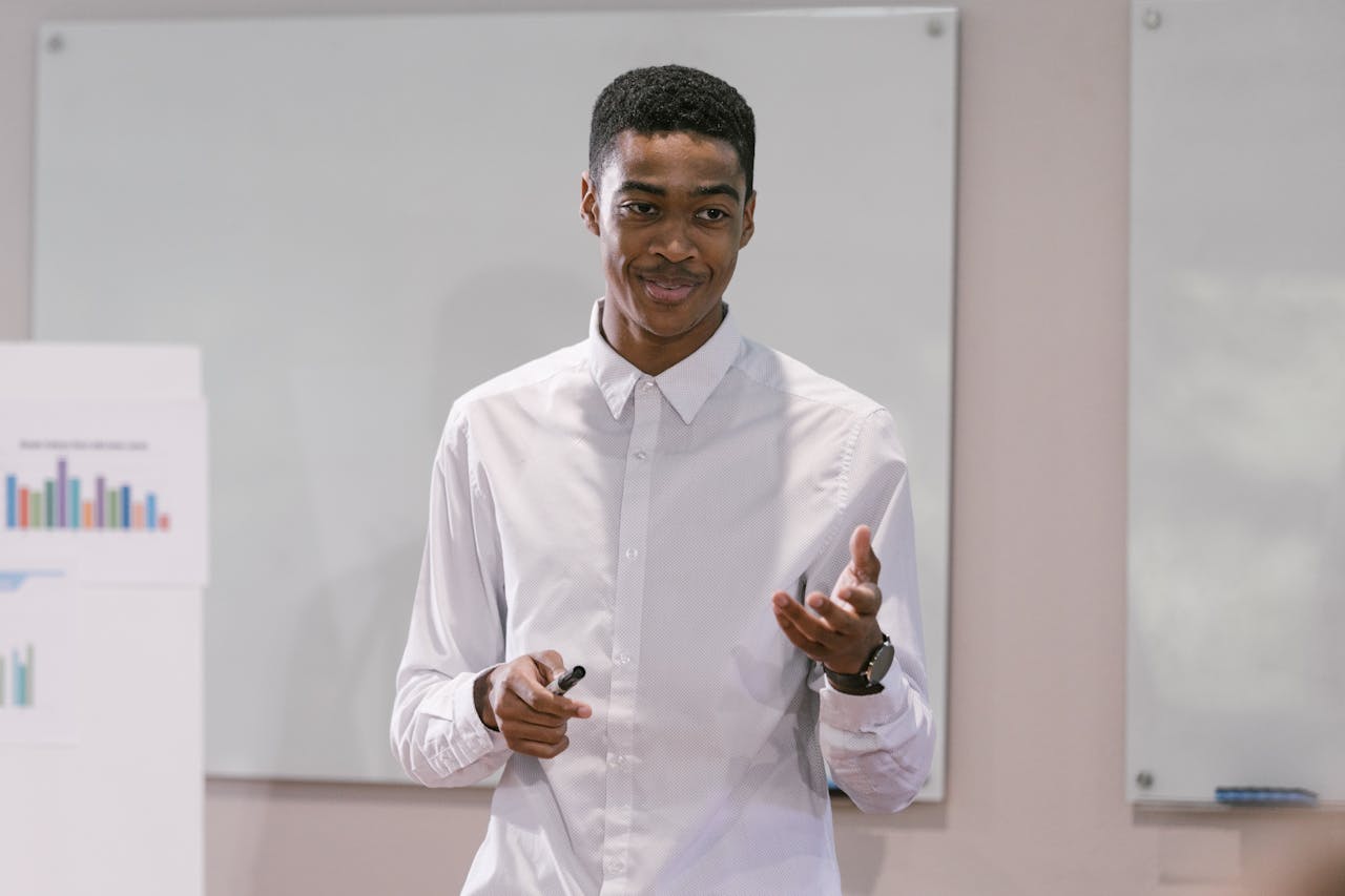 A confident young man presenting in a business setting, engaging with an audience.