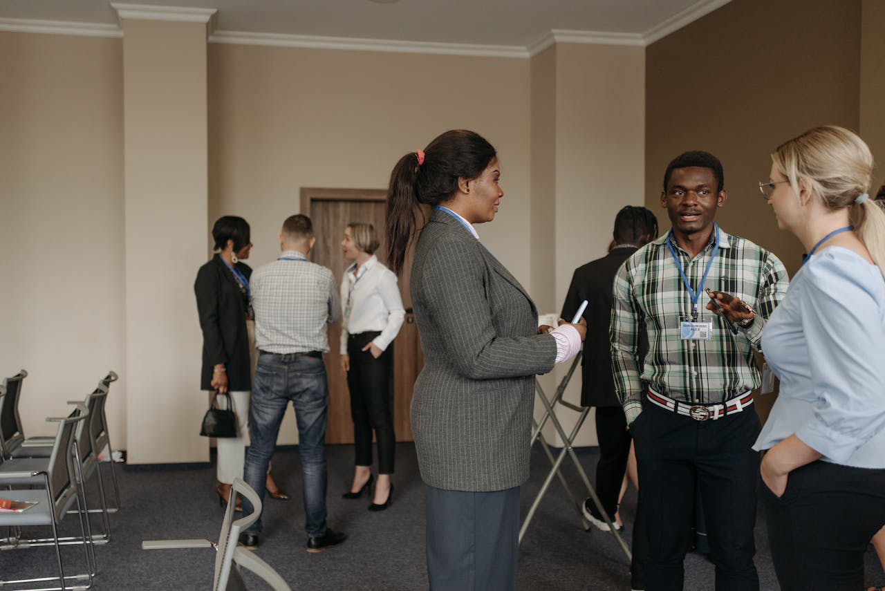 Professionals engaging in conversation at a diverse business conference with corporate attire indoors.